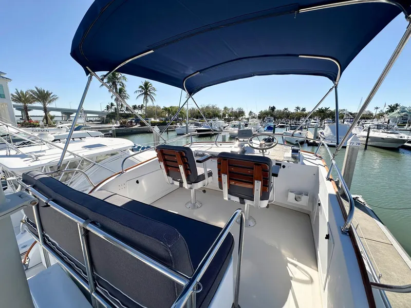 Slide: The Image of 2000 Legacy Yachts 40 Sedan with blue canopy, docked in a marina. - 12