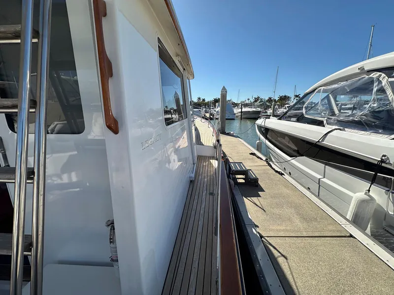 Slide: The Image of 2000 Legacy Yachts 40 Sedan docked, showcasing sleek design and wooden deck details. - 19