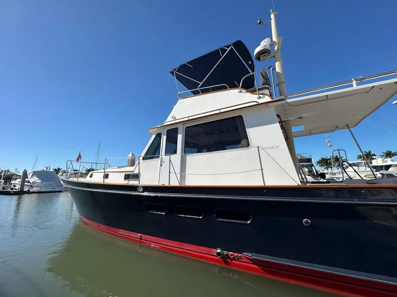 Slide: The Image of 2000 Legacy Yachts 40 Sedan in marina, blue hull, red stripe, clear sky background. - 2