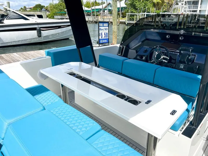 Slide: The Image of 2023 De Antonio Yachts D28 Open with blue seating and sleek interior design at a marina. - 14
