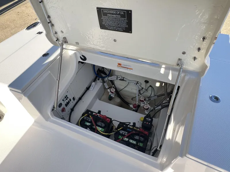 Slide: The Image of 2024 Robalo 246 Cayman boat battery compartment with open hatch and visible wiring. - 12
