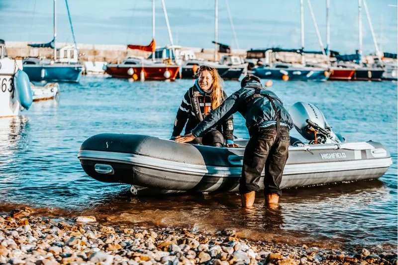 Slide: The Image of Two people on a Highfield Classic 360 boat at the shore. - 3