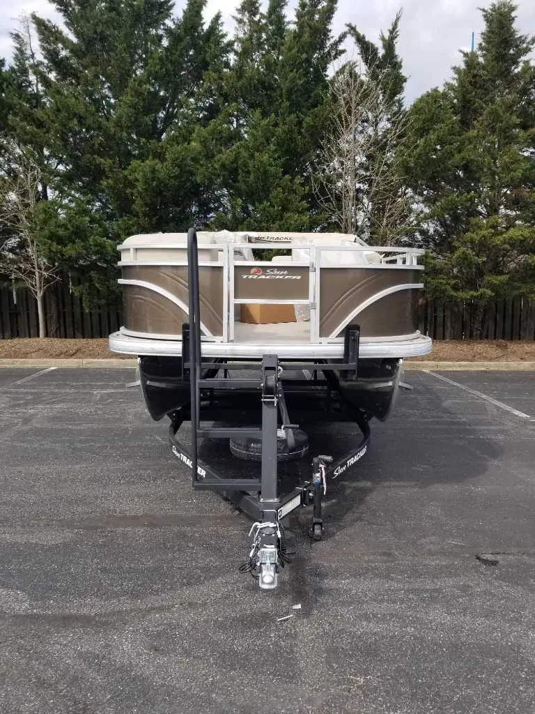 The Image of 2025 Sun Tracker SportFish 20 DLX pontoon boat on trailer, parked in lot. - 0