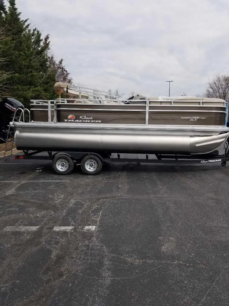 Slide: The Image of 2025 Sun Tracker SportFish 20 DLX pontoon boat on trailer in parking lot. - 2