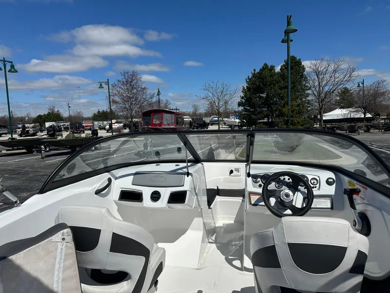 Slide: The Image of 2024 Tahoe 185 S boat interior with steering wheel and seating, parked outdoors under blue sky. - 3