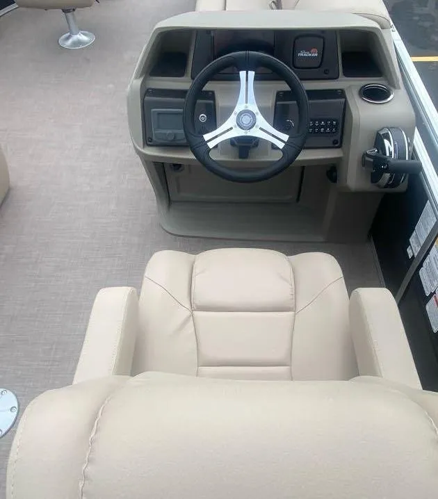 Slide: The Image of 2024 Sun Tracker SportFish 20 DLX boat interior with beige seating and steering console. - 2
