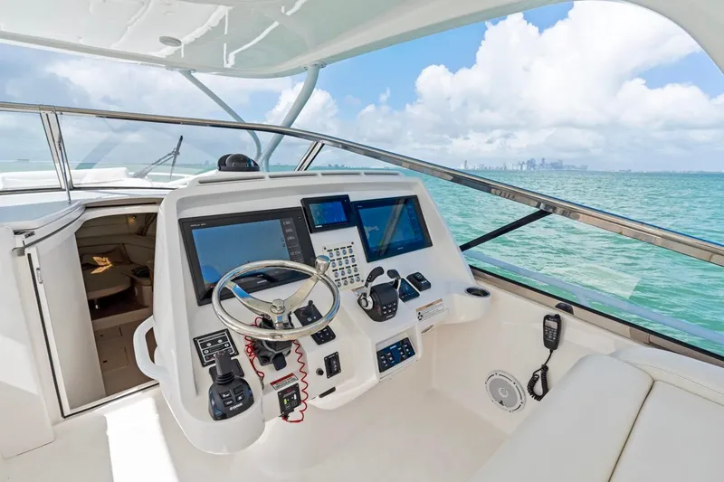 Slide: The Image of 2018 Intrepid 475 Sport Yacht helm with advanced navigation systems, overlooking ocean and skyline. - 13