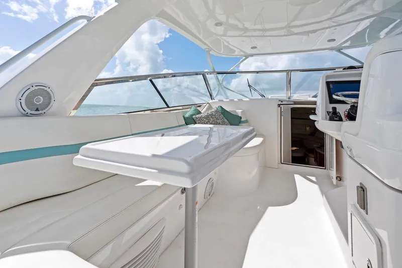 Slide: The Image of 2018 Intrepid 475 Sport Yacht interior with sleek seating and table, under a sunny sky. - 17