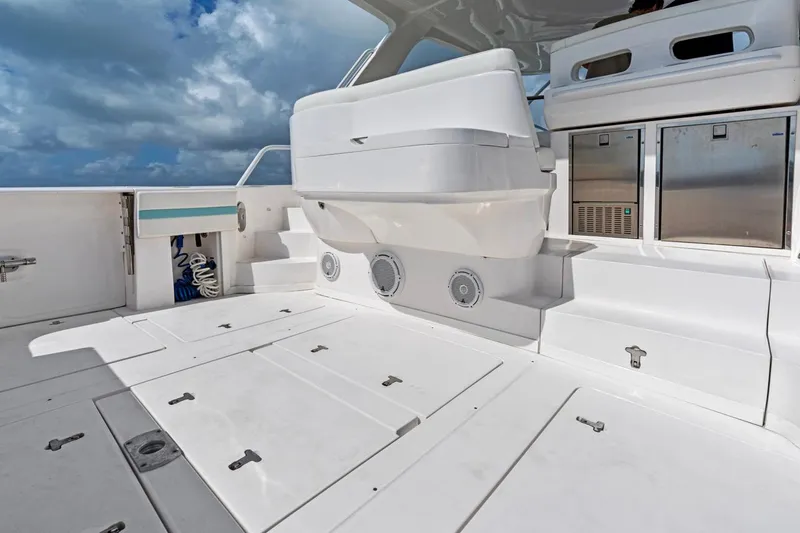 Slide: The Image of 2018 Intrepid 475 Sport Yacht deck with storage compartments and seating under a cloudy sky. - 20