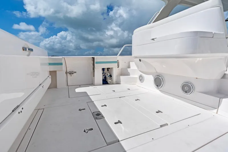 Slide: The Image of 2018 Intrepid 475 Sport Yacht deck with storage compartments under a cloudy sky. - 24