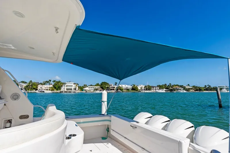 Slide: The Image of 2018 Intrepid 475 Sport Yacht with canopy, overlooking serene waterfront homes. - 31