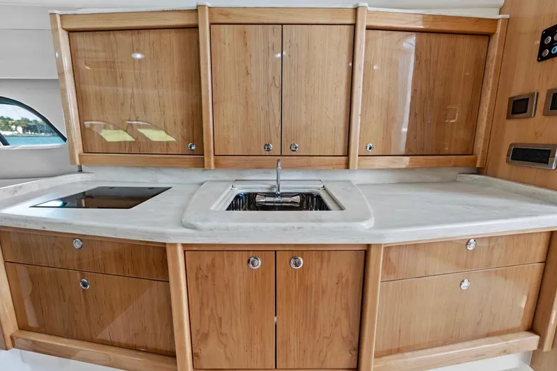 Slide: The Image of 2018 Intrepid 475 Sport Yacht kitchen with wooden cabinets and modern sink. - 46