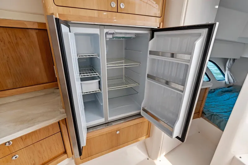 Slide: The Image of Open refrigerator in 2018 Intrepid 475 Sport Yacht, showcasing spacious interior and wooden cabinetry. - 48