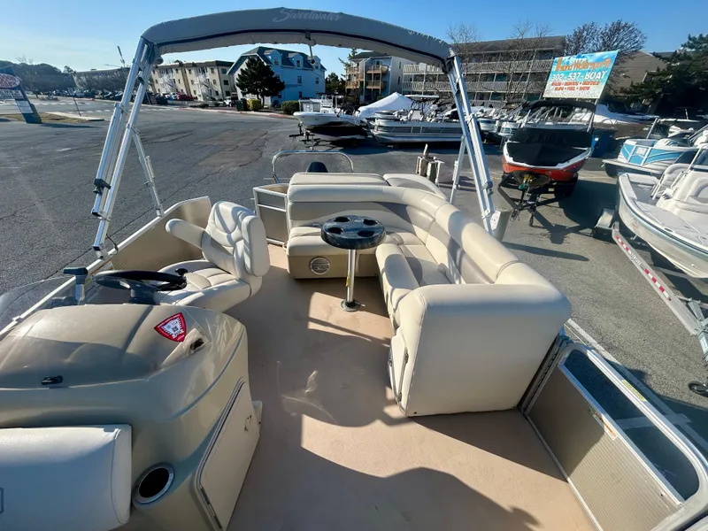 Slide: The Image of 2016 Godfrey SWEETWATER 200 pontoon boat with beige seating and canopy, parked in a marina. - 11