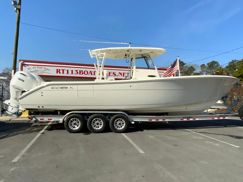 The Image of 2025 Cobia 320 Center Console boat on trailer in parking lot. - 1