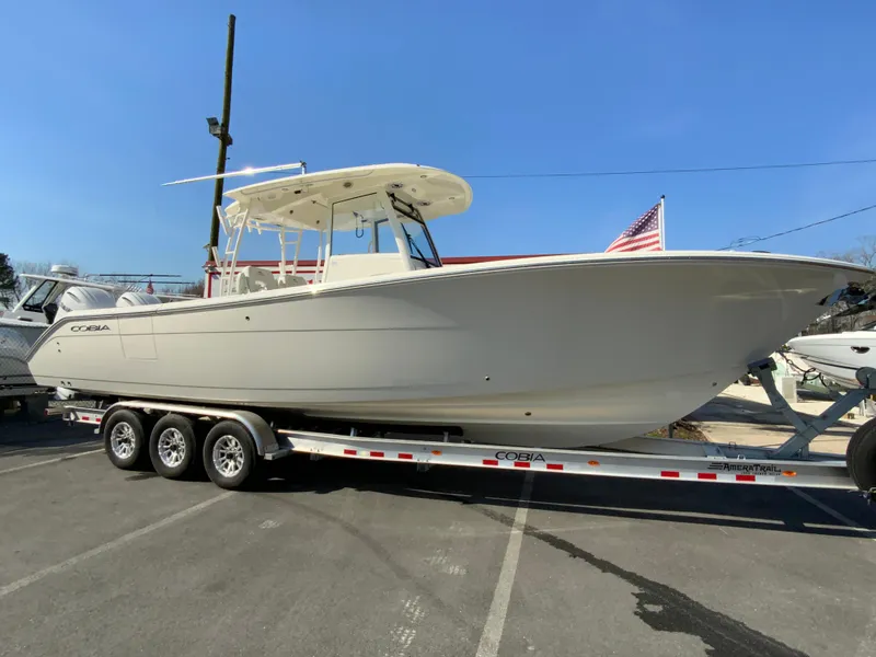 Slide: The Image of 2025 Cobia 320 Center Console boat on trailer, parked outdoors. - 2