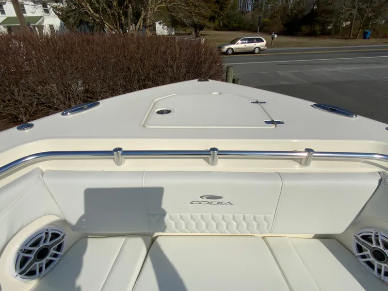 Slide: The Image of 2025 Cobia 320 Center Console boat, front seating area with speakers and storage hatch. - 27