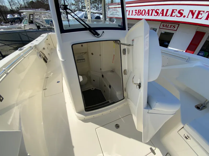 Slide: The Image of 2025 Cobia 320 Center Console boat with open cabin door at dealership. - 34