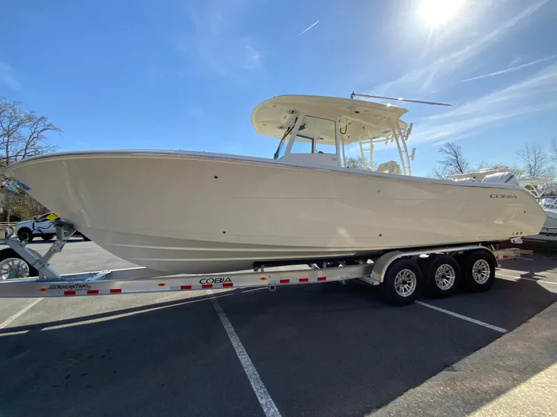 Slide: The Image of 2025 Cobia 320 Center Console boat on a trailer under a clear blue sky. - 6