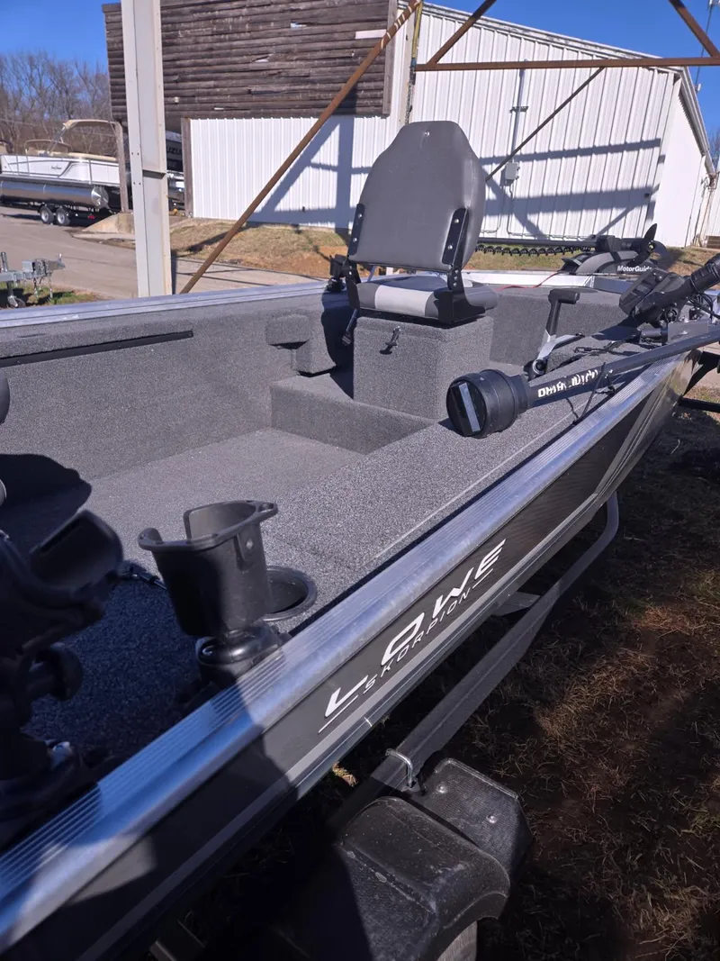 Slide: The Image of 2023 Lowe Skorpion 16 fishing boat with seating and rod holders, parked outdoors. - 8