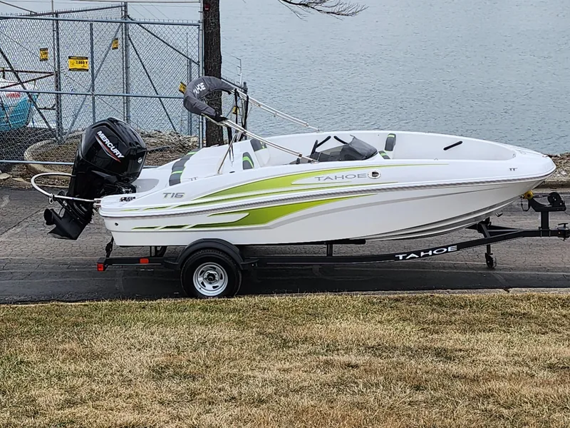 Slide: The Image of 2023 Tahoe T16 boat on trailer by lakeside, featuring sleek design and vibrant accents. - 0