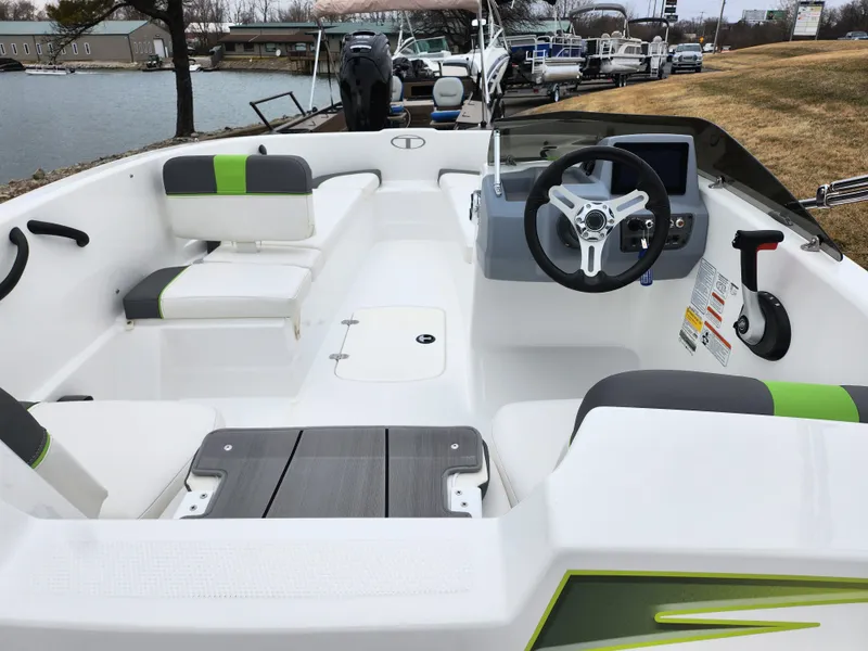 Slide: The Image of 2023 Tahoe T16 boat interior with modern seating and steering, docked by a lake. - 10