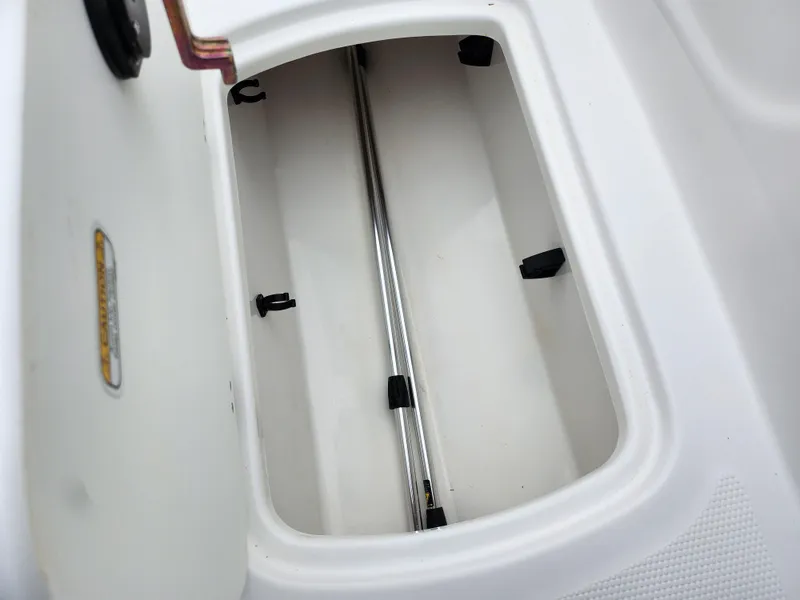 Slide: The Image of 2023 Tahoe T16 storage compartment with white interior and metal rod. - 15