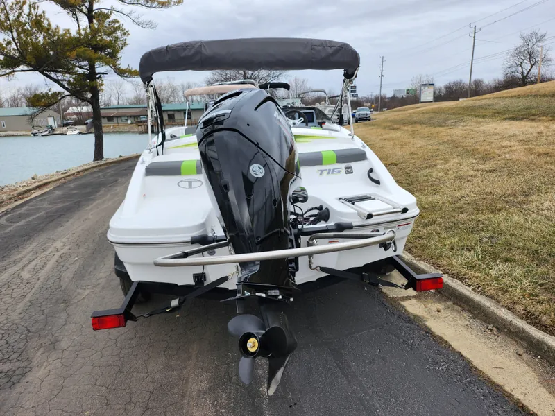 Slide: The Image of 2023 Tahoe T16 boat with outboard motor on a trailer by a lakeside road. - 2