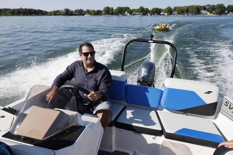 Slide: The Image of Man driving 2025 Starcraft SV 16 OB boat on a lake, towing a yellow inflatable. - 8