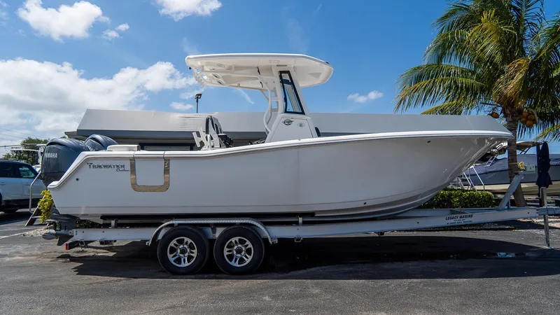 The Image of 2025 Tidewater 256 LXF boat on trailer, parked outdoors under blue sky. - 0