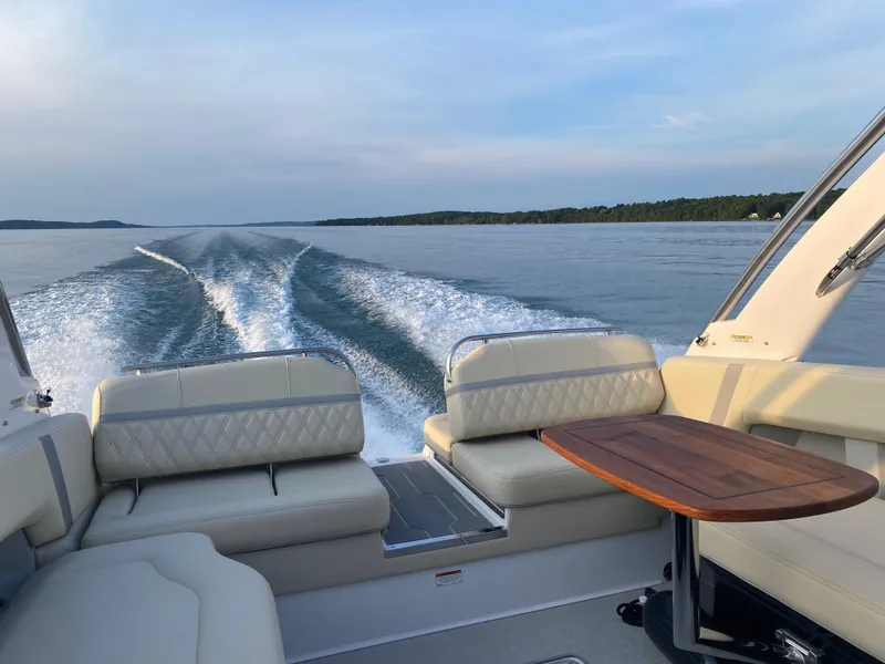 Slide: The Image of 2021 Regal 2800 Bowrider cruising on a serene lake with elegant seating and table. - 10