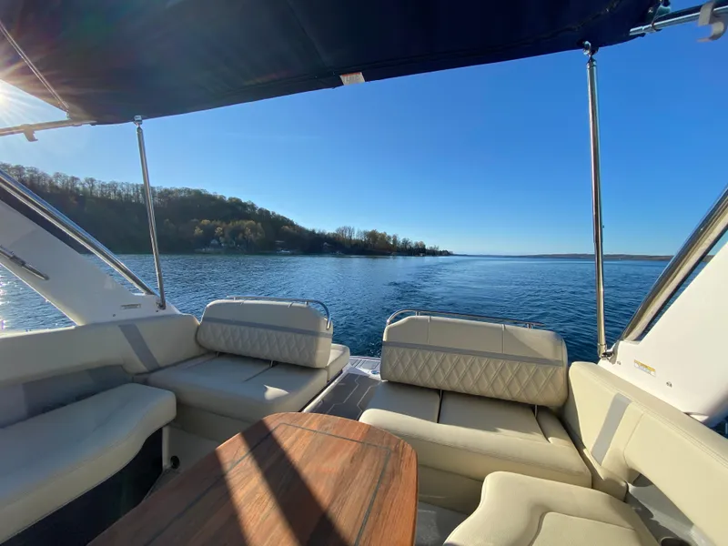 Slide: The Image of 2021 Regal 2800 Bowrider interior with lake view, featuring comfortable seating and wooden table. - 11