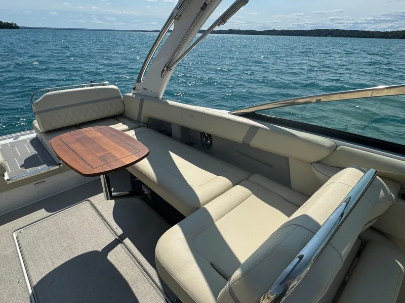 Slide: The Image of 2021 Regal 2800 Bowrider interior with beige seating and wooden table on a sunny day. - 12