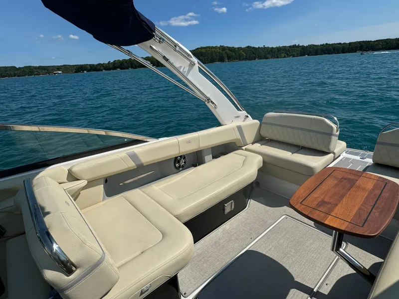 Slide: The Image of 2021 Regal 2800 Bowrider interior with beige seating and wooden table on a sunny day. - 13