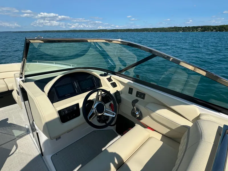 Slide: The Image of 2021 Regal 2800 Bowrider boat interior with steering wheel, dashboard, and lake view. - 14