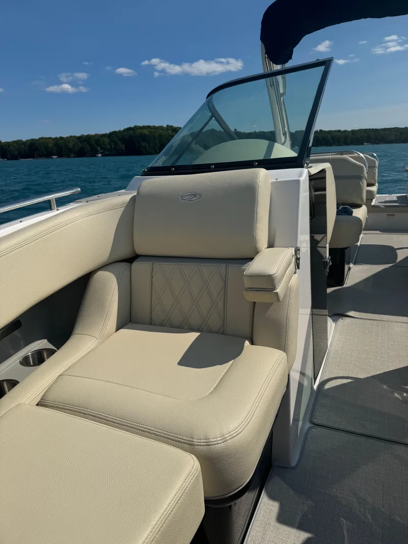 Slide: The Image of 2021 Regal 2800 Bowrider boat interior with beige seating on a sunny day. - 23