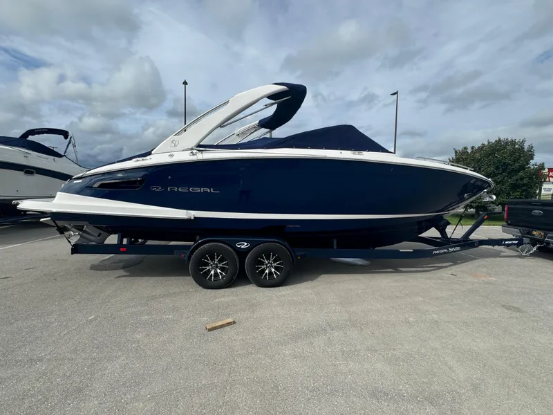 Slide: The Image of 2021 Regal 2800 Bowrider boat on trailer, parked outdoors under cloudy sky. - 6