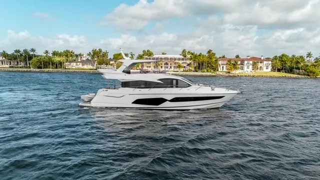 Slide: The Image of 2019 Sunseeker Manhattan 66 yacht cruising on open water, rear view. - 2