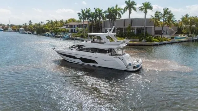 Slide: The Image of 2019 Sunseeker Manhattan 66 yacht cruising on open water under a clear sky. - 6