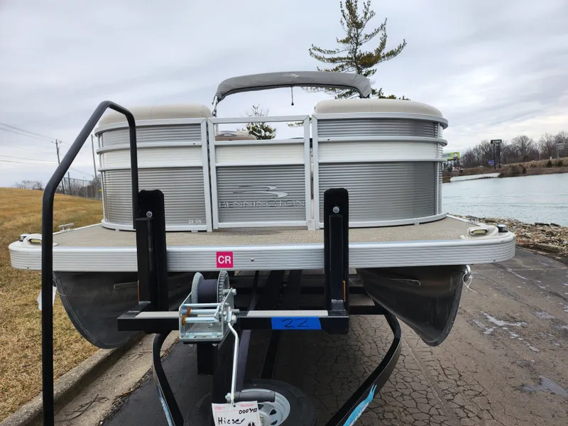 Slide: The Image of 2019 Bennington SX 22 Cruise and Fish pontoon boat on trailer by a lake. - 6