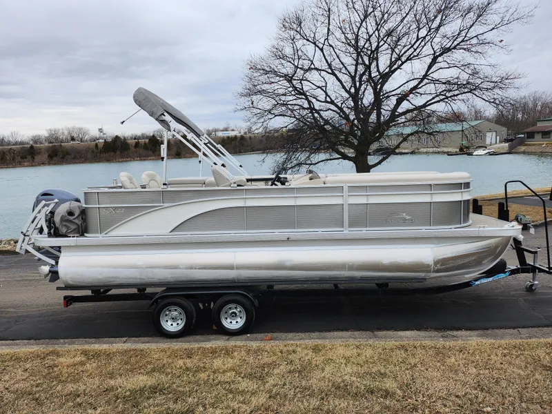 Slide: The Image of 2019 Bennington SX 22 Cruise and Fish pontoon boat on trailer by a lake. - 9