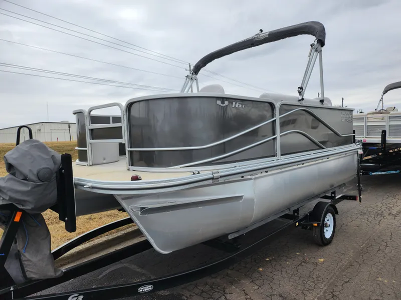 Slide: The Image of 2019 SunCatcher V16 Fish pontoon boat on trailer, gray exterior, overcast sky. - 5