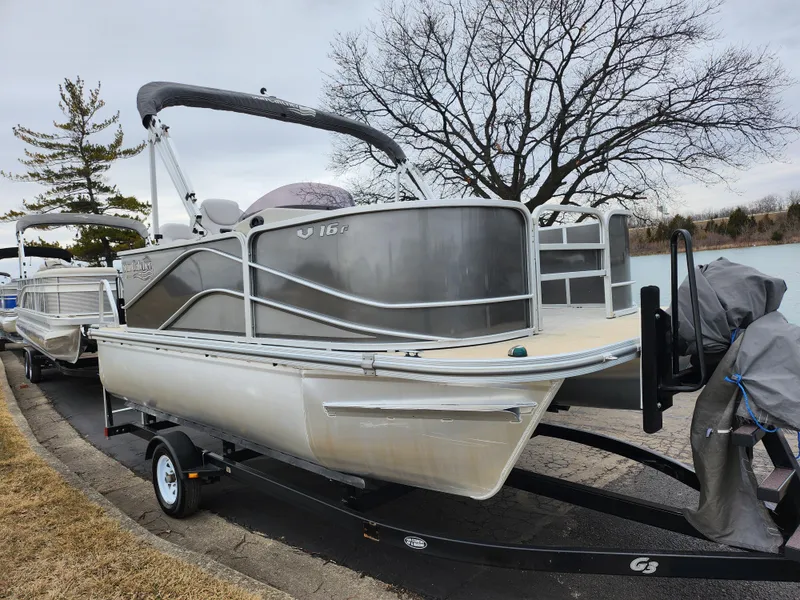 Slide: The Image of 2019 SunCatcher V16 Fish pontoon boat on trailer by lakeside, overcast sky. - 8