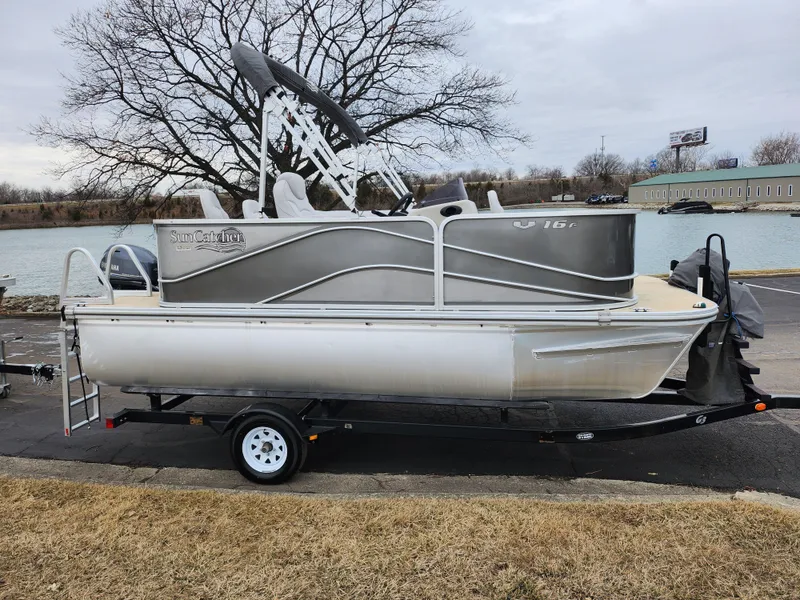 Slide: The Image of 2019 SunCatcher V16 Fish pontoon boat on trailer by a riverbank. - 9
