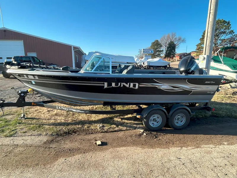 Slide: The Image of 2009 Lund 1950 Tyee Grand Sport boat on trailer, parked outdoors. - 2