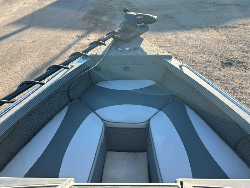 Slide: The Image of 2009 Lund 1950 Tyee Grand Sport boat interior with cushioned seating and trolling motor. - 8