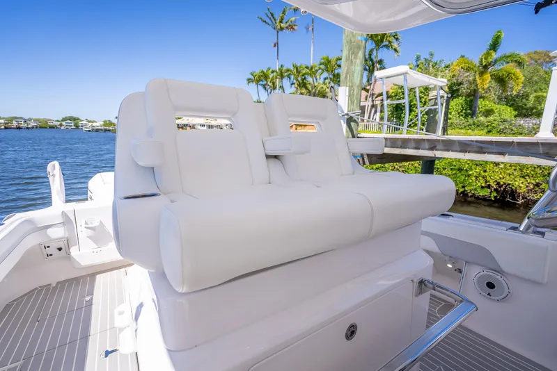 Slide: The Image of 2020 Intrepid 407 Cuddy boat with white seating, docked by a scenic waterfront. - 44