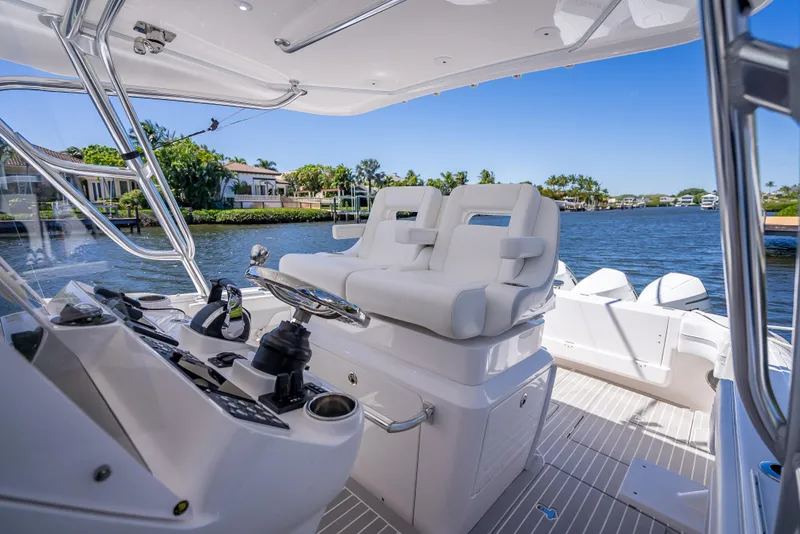 Slide: The Image of 2020 Intrepid 407 Cuddy boat interior with helm and seating, overlooking serene waterfront. - 49