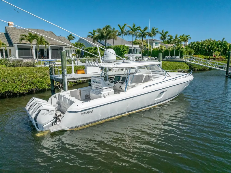 Slide: The Image of 2020 Intrepid 407 Cuddy boat docked near waterfront homes, surrounded by lush greenery. - 5