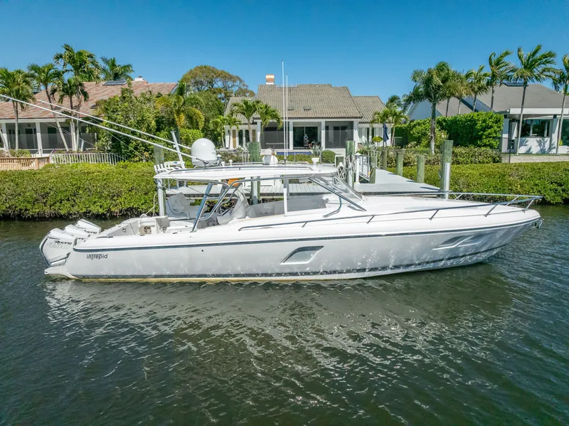 Slide: The Image of 2020 Intrepid 407 Cuddy boat docked by waterfront homes, clear blue sky. - 6